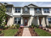 Charming townhome showcases a well manicured lawn and a welcoming front entrance with a red front door at 9338 Bolshoi Aly, Winter Garden, FL 34787