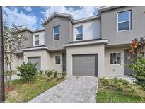 Two-story townhome featuring a one car garage, landscaped front yard, and neutral gray and beige exterior paint at 1217 S Station Pl # 502, Orlando, FL 32809