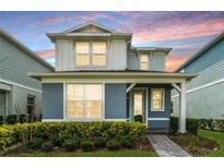 Charming two-story home with a covered entry and lush landscaping at sunset at 14218 Lanikai Beach Dr, Orlando, FL 32827