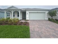 Charming single-story home featuring a brick driveway, landscaped front yard, and a two-car garage at 2765 Redblush Ter, St Cloud, FL 34772