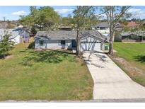 Charming single-story home with a well-manicured lawn and a long driveway leading to a two-car garage at 2801 W Covington Dr, Deltona, FL 32738