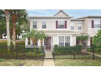 Charming two-story townhouse featuring a black metal fence, lush landscaping, and a welcoming front entrance at 4527 Sunset Ln, Oviedo, FL 32765