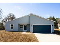 Charming single-story home featuring a blue garage door, modern design, and well-maintained front yard at 656 Marion Oaks Mnr, Ocala, FL 34473