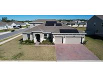 Inviting single-story home featuring a well-manicured lawn, solar panels, and an attached two-car garage at 4897 Gilded Jewel Dr, Mount Dora, FL 32757
