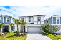 Charming two-story home with a two car garage, palm trees, and a well manicured lawn at 7219 Oakmoss Loop, Davenport, FL 33837