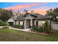 Charming single-story home featuring a stone entryway, well-manicured landscaping, and a two-car garage at 1222 Shorecrest Cir, Clermont, FL 34711