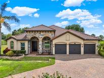 Beautiful home featuring a three-car garage, stone accents, and a well-manicured lawn and landscape at 16548 Caravaggio Loop, Montverde, FL 34756
