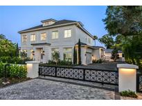 Stunning, light-colored, two-story home featuring manicured landscaping and a gated entrance at 1660 Palmer Ave, Winter Park, FL 32789