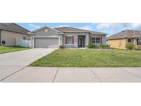 Charming single-story home with a well-manicured lawn and a two-car garage on a sunny day at 3664 Apopka Ridge Cir, Apopka, FL 32703