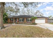 Charming brick home featuring a two-car garage, solar panels, and a well-maintained front yard at 432 Wilderness Dr, Longwood, FL 32779