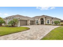 Stunning home featuring a three-car garage, paver driveway, lush landscaping, and elegant architectural details at 534 Two Lakes Ln, Eustis, FL 32726