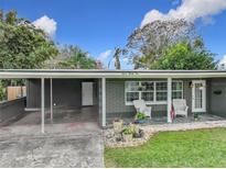 Charming single-story home featuring a carport, front porch with white rocking chairs, and freshly manicured lawn at 724 Alfred Dr, Orlando, FL 32810