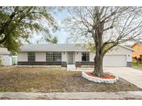 Charming single-story home featuring a well-maintained front yard, neutral paint, and mature trees at 8874 Hillsdale Dr, Orlando, FL 32818