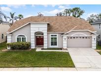 Charming single-story home with a red front door, manicured lawn, and attached two car garage at 13506 Crystal River Dr, Orlando, FL 32828