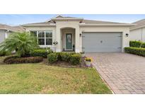 Charming one-story home with a well-manicured lawn, beautiful landscaping, and a brick-paved driveway at 2017 Flora Pass Pl, Kissimmee, FL 34747