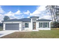 Charming single-story home showcasing a gray garage door, modern front door, and well-manicured lawn at 245 Marion Oaks Golf Rd, Ocala, FL 34473