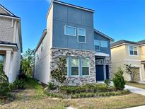 Modern two-story home featuring a blue exterior, stone accents, and well-maintained landscaping at 8949 Coconut Breeze Dr, Kissimmee, FL 34747