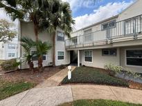Condominium exterior featuring the building, sidewalk, manicured landscaping and healthy mature palm trees at 2564 Woodgate Blvd # 102, Orlando, FL 32822