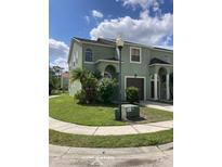 Charming two-story townhouse featuring a well-manicured lawn, arched entryway, and attached garage at 4324 Paradise Cove Ct, Kissimmee, FL 34746