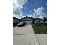 Charming single-story home with a two-car garage, landscaped yard, and concrete driveway at 597 Pine Tree Blvd, Lake Alfred, FL 33850