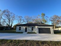 Charming single-story home with a well-maintained lawn, a gray exterior, and an attached garage at 6425 Curtis St, Orlando, FL 32807