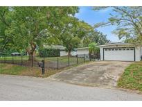 Charming home exterior with a fenced yard, mature trees, and a two-car garage at 701 Denton Rd, Winter Park, FL 32792