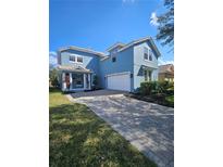 Charming two-story home with a brick driveway, manicured lawn, and a welcoming front porch at 7187 Wild Strawberry Run, Winter Garden, FL 34787