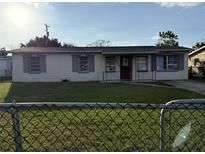 Charming single-story home with a red front door, tidy lawn, and a chain-linked fence at 7200 Ravenna Ave, Orlando, FL 32819