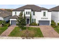 Stately two-story home featuring a manicured lawn, gray roof, and two-car garage at 8390 Ludington Cir, Orlando, FL 32836
