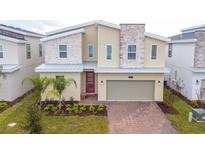 Stunning two-story home with stone accents, a red door, a paver driveway, and a well-manicured front yard at 8824 Cruden Bay Ct, Davenport, FL 33896