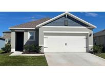 Charming home showcasing a two-car garage with a white door and complemented by lush green landscaping at 1972 Victoria St, Davenport, FL 33837