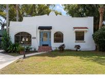 Charming single-story home with a light blue door, stucco exterior, arched windows, and a well-manicured lawn at 2100 Sheridan Rd, Mount Dora, FL 32757