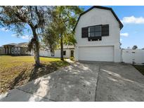 Charming home featuring white siding, an attached two-car garage, and a well-maintained front yard with mature trees at 2531 Ludlow St, Deltona, FL 32738