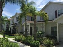 Townhome exterior with well-maintained landscaping, palm trees, and light-colored siding at 5352 Diplomat Ct # 107, Kissimmee, FL 34746