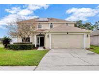 Inviting two-story home with a well-manicured lawn, lush landscaping, and a convenient two-car garage at 131 Woodbury Pines Cir, Orlando, FL 32828