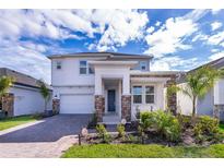Beautiful two-story home with a brick driveway, landscaped yard, and a covered entryway at 187 Aces High Ln, Davenport, FL 33896