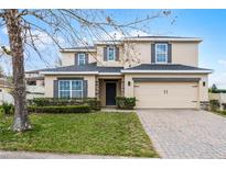 Charming two-story home with neutral stucco, manicured lawn, paver driveway, and attached two-car garage at 9518 Lynwood St, Clermont, FL 34711