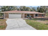 Charming brick home with an attached two-car garage and well-maintained front yard at 11595 Sw 134 Ct, Dunnellon, FL 34432