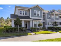 Charming two-story townhome with a blend of gray and blue siding and landscaped front yard at 14031 Centerline Dr, Orlando, FL 32827