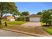 Charming single-story home with a well-manicured lawn and a brick-paved driveway at 211 S Deerwood Ave, Orlando, FL 32825