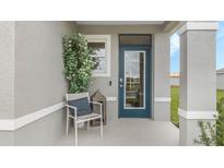 Inviting front porch featuring a chair, accent table, and a stylish blue front door at 3603 Salvia Ct, Tavares, FL 32778