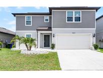 Two-story home featuring a gray exterior, a two-car garage, and a well-maintained front yard with decorative landscaping at 5663 Keaton Springs Dr, Lakeland, FL 33811