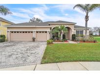 Charming home featuring a paver driveway, lush lawn, manicured landscaping, and a welcoming front porch at 719 Postrio Way, Ocoee, FL 34761