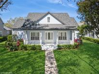 Charming single-story home with a manicured lawn and inviting front porch with white columns and lush green hedges at 11237 Camden Park Dr, Windermere, FL 34786