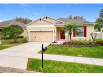 Charming single-story home with a manicured lawn, red shutters, and a two-car garage at 20945 Oldenburg Loop, Mount Dora, FL 32757