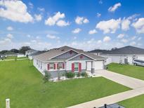 Charming single-story home with a well-manicured lawn, complemented by red shutters and a two car garage at 2220 Gladiolus Ln, Mascotte, FL 34753