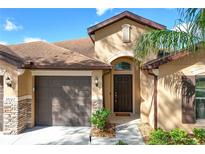 Charming home exterior with a two-car garage, manicured landscaping, and a welcoming front door at 32107 Spring Meadow Ct., Sorrento, FL 32776