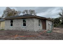 View of an unfinished block home with a new roof and modern windows ready for customization at 5238 2Nd St, Orlando, FL 32810