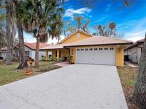 Charming home features a two-car garage, a well-manicured lawn, and beautiful landscaping with palm trees at 629 Nighthawk Cir, Winter Springs, FL 32708