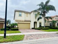Two-story home with a two car garage, tile roof, and a paver driveway at 12059 Uleta Ln, Orlando, FL 32827